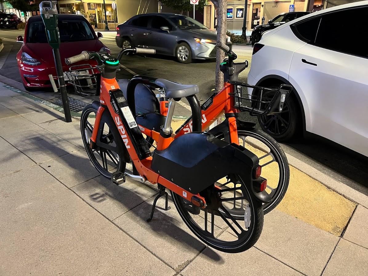 SPIN bikes parked along a sidewalk on Broadway in Burlingame.