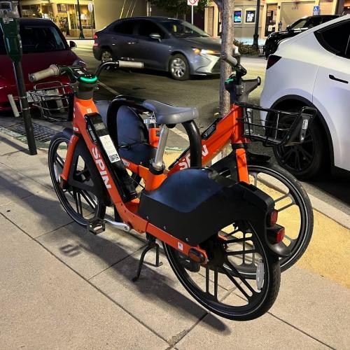 SPIN bikes parked along a sidewalk on Broadway in Burlingame.