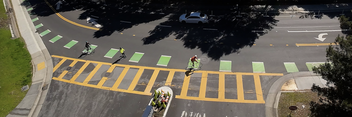 Bikes crossing a street with a dedicated green lane.